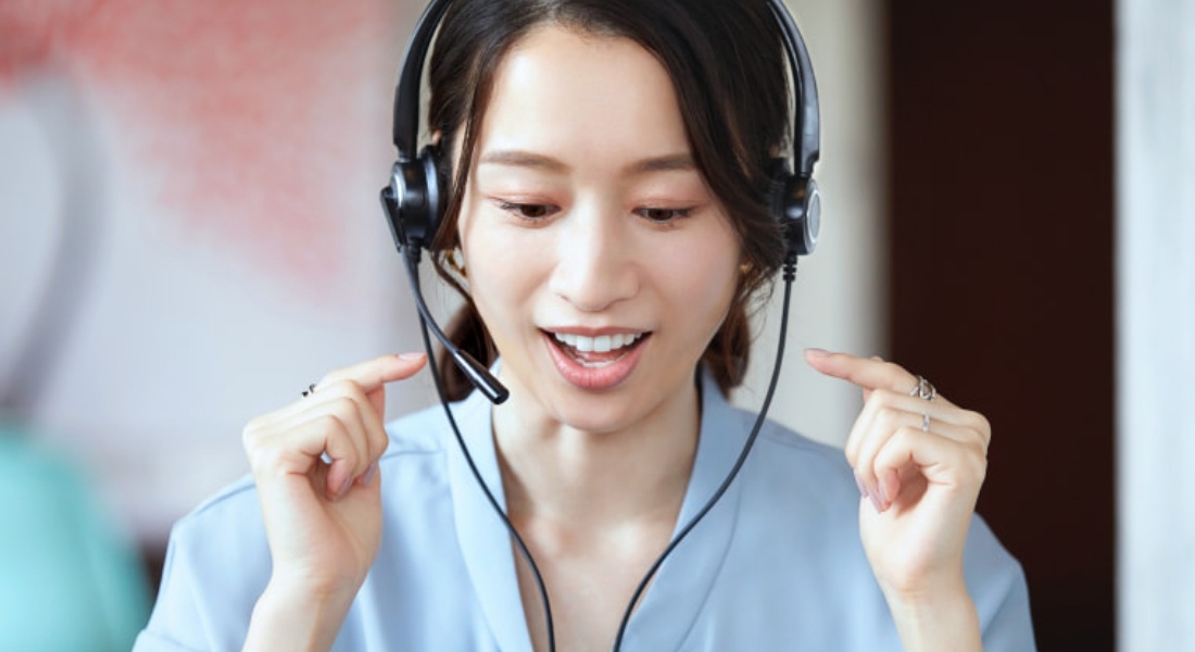 写真:ヘッドセットを着けて英語の発音練習を行う女性。真剣な表情で発音を確認している。